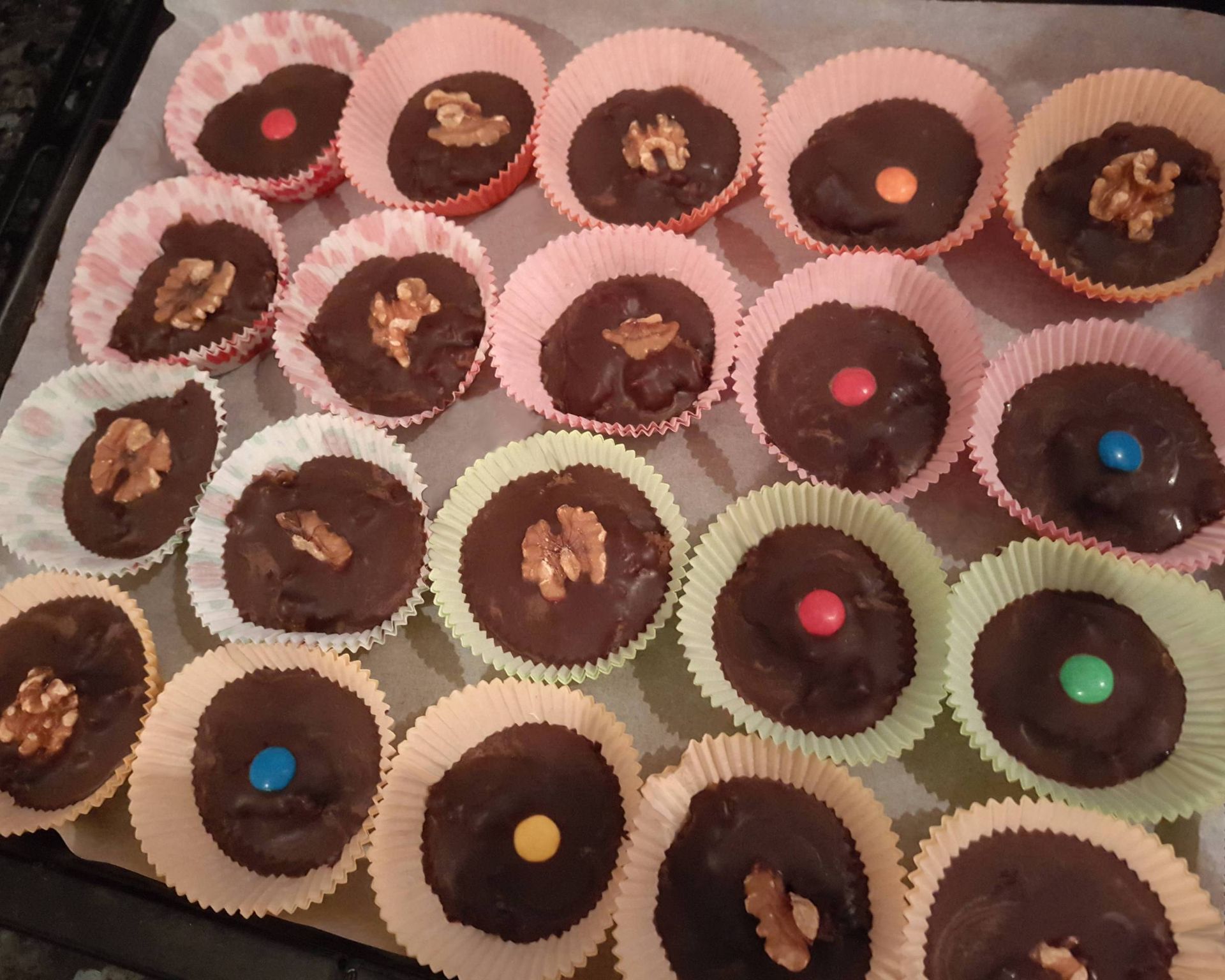 Čokoládové koláčiky v košíčkoch plnené kávovou plnkou, ozdobené vlašskými orechmi a lentilkami