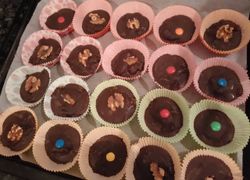 Čokoládové koláčiky v košíčkoch plnené kávovou plnkou, ozdobené vlašskými orechmi a lentilkami