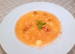 Hlboký tanier plný kapustovej polievky so zemiakmi, na krúžky nakrájaná klobása