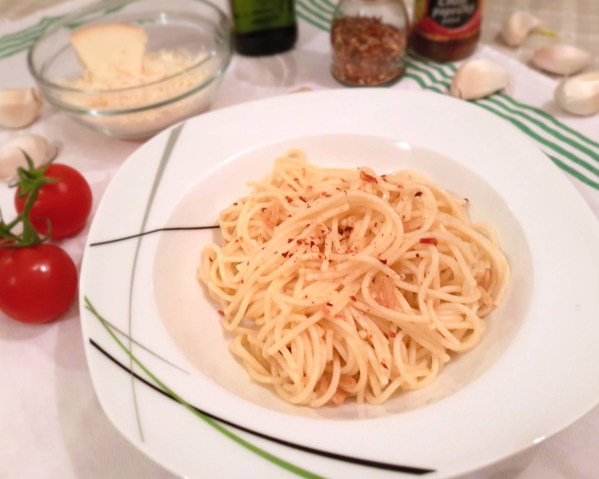 Uvarené cestoviny aglio olio na tanieri posypané drvenými sušenými chilli papričkami.