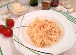 Uvarené cestoviny aglio olio na tanieri posypané drvenými sušenými chilli papričkami.