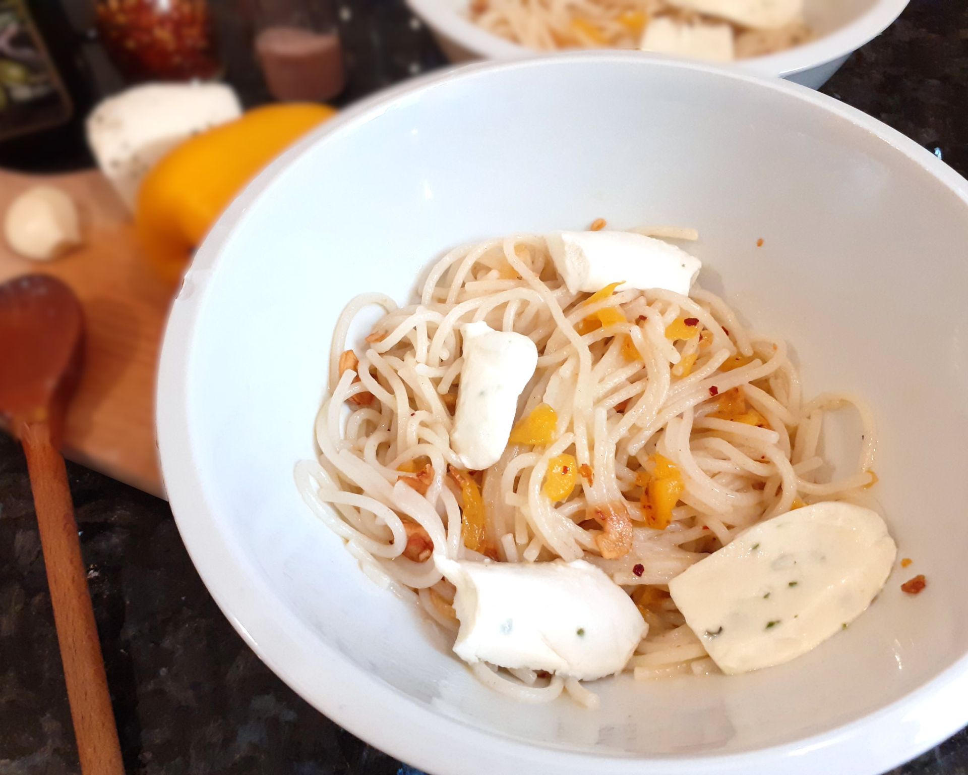 Uvarené cestoviny špagety s praženou paprikou na olivovom oleji. Ako príloha sa podáva syr mozzarella.