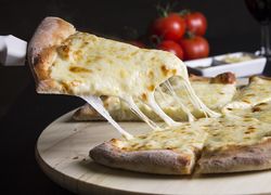 Biela pizza so smotanou a syrom, v pozadí cherry paradajky