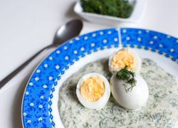 Omáčka z kôpru na tanieri s modro-bielym okrajom, na vrchu uvarené vajíčka posypané kôprom