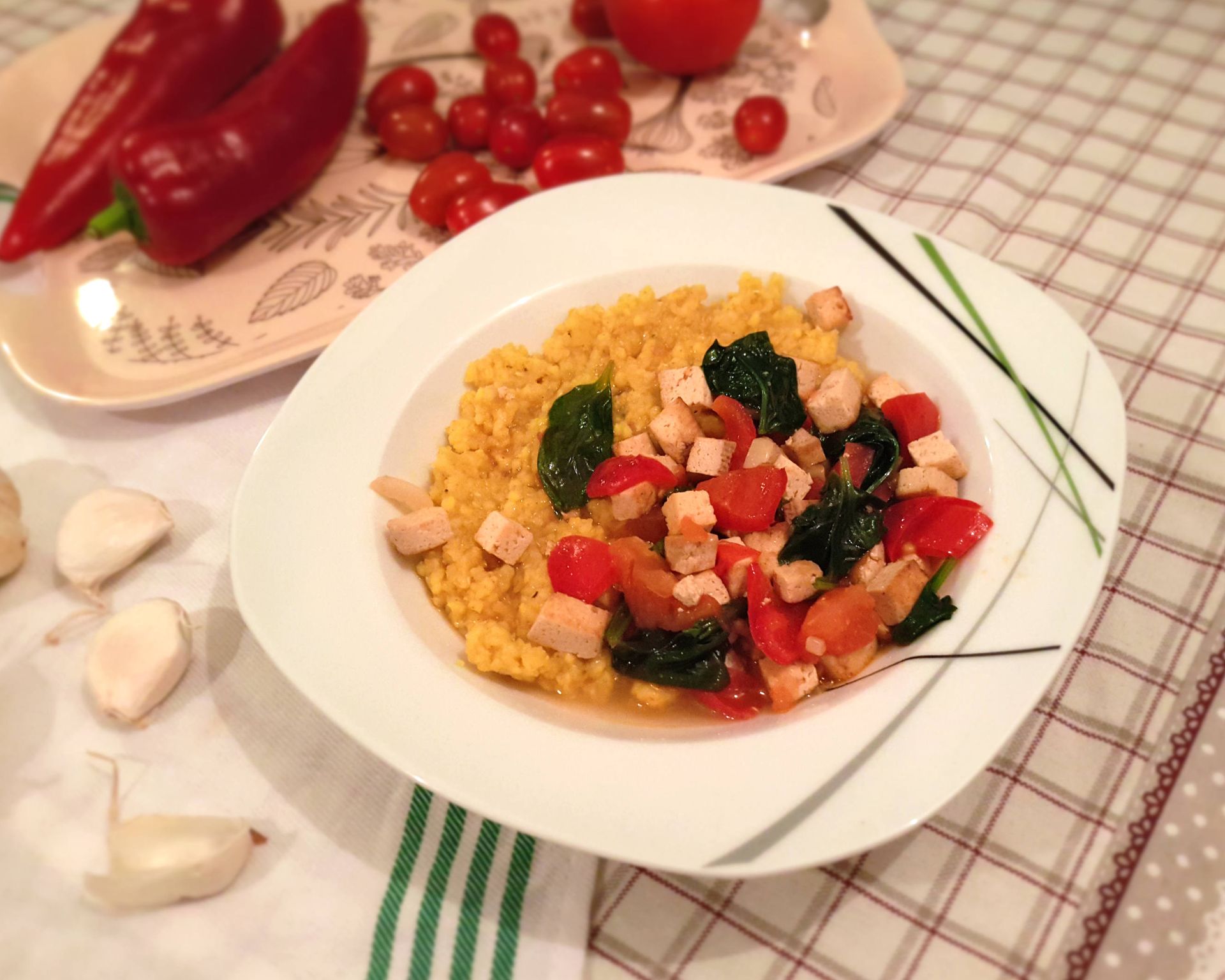 Vegánsky tanier plný čerstvo uvareného pšena so zmesou tofu, papriky, cesnaku a baby-špenátu.