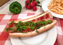 Párok v prekrojenom rožku s kečupom - americký "horúci pes", rukola a v pozadí domáce hranolky