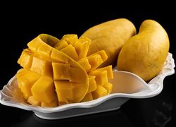 Nakrojené mango - kráľovskéhé ovocie. Za nimi celé mangá.